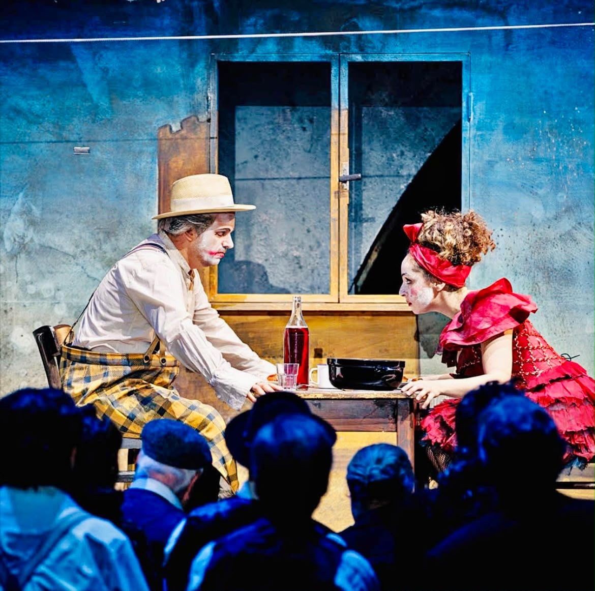 In a red costume facing a clown at a table