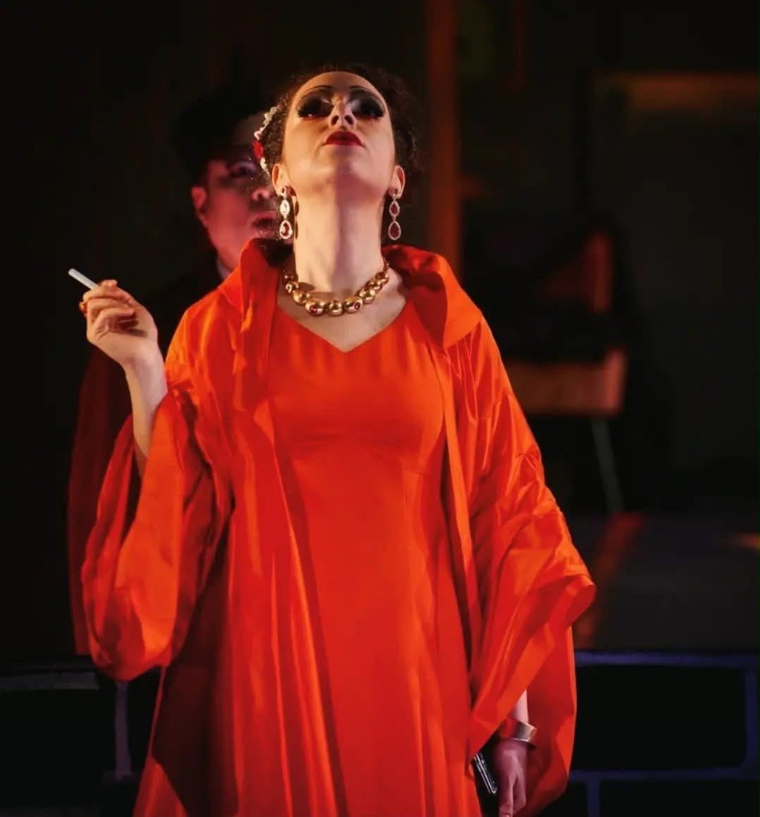 In a flowing orange robe with gold jewellery