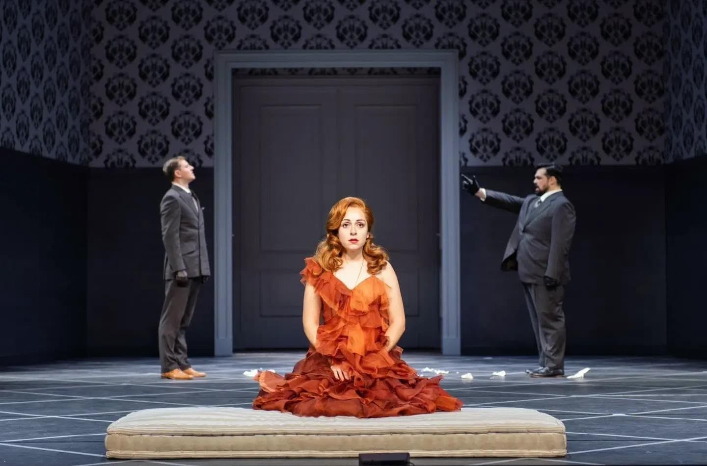 Kneeling in a rust gown between two men in suits