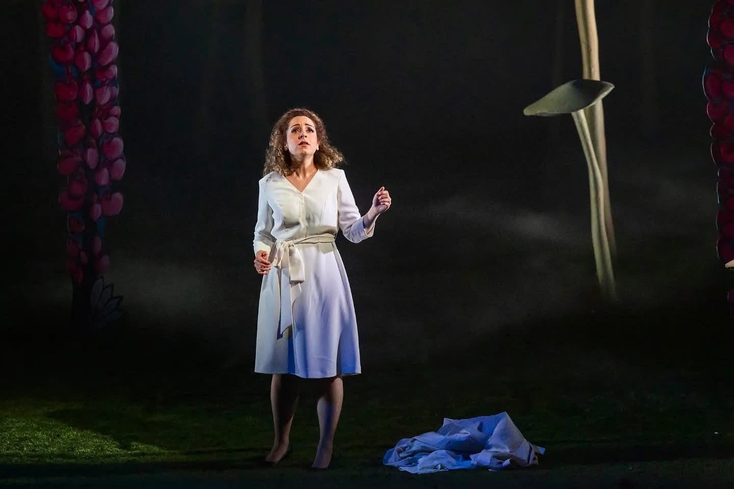 In a white dress under a spotlight